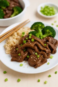A plate of shaved beef recipes served with brown rice, steamed broccoli, and chopped green onions.