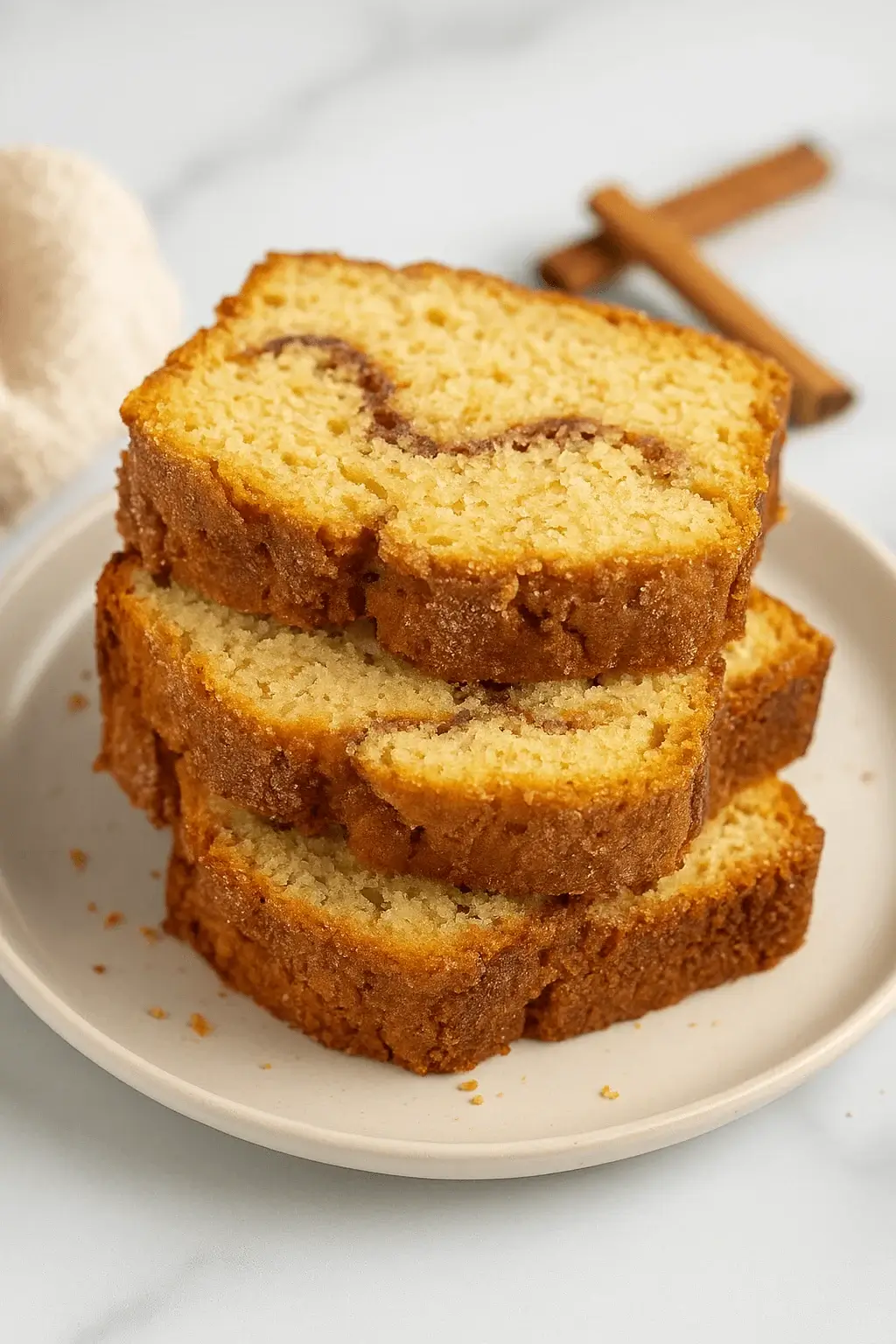 Stack of three slices from an Amish Cinnamon Bread Recipe on a white plate with a cinnamon swirl visible in each slice.