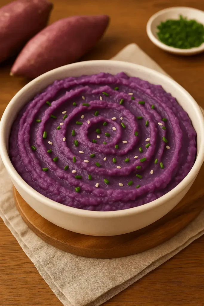 A creamy bowl of mashed purple sweet potatoes topped with chives and sesame seeds – part of a vibrant Purple Sweet Potato Recipe.