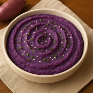 A creamy swirl of mashed purple sweet potatoes topped with chives and sesame seeds - part of a comforting Purple Sweet Potato Recipe.